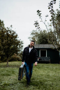 Meneer komt tussen de fruitbomen door aanlopen met een ladder