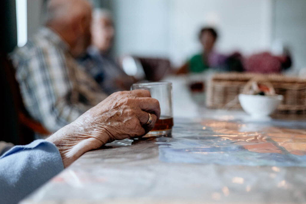 Hand van oude mevrouw houdt een kopje thee vast
