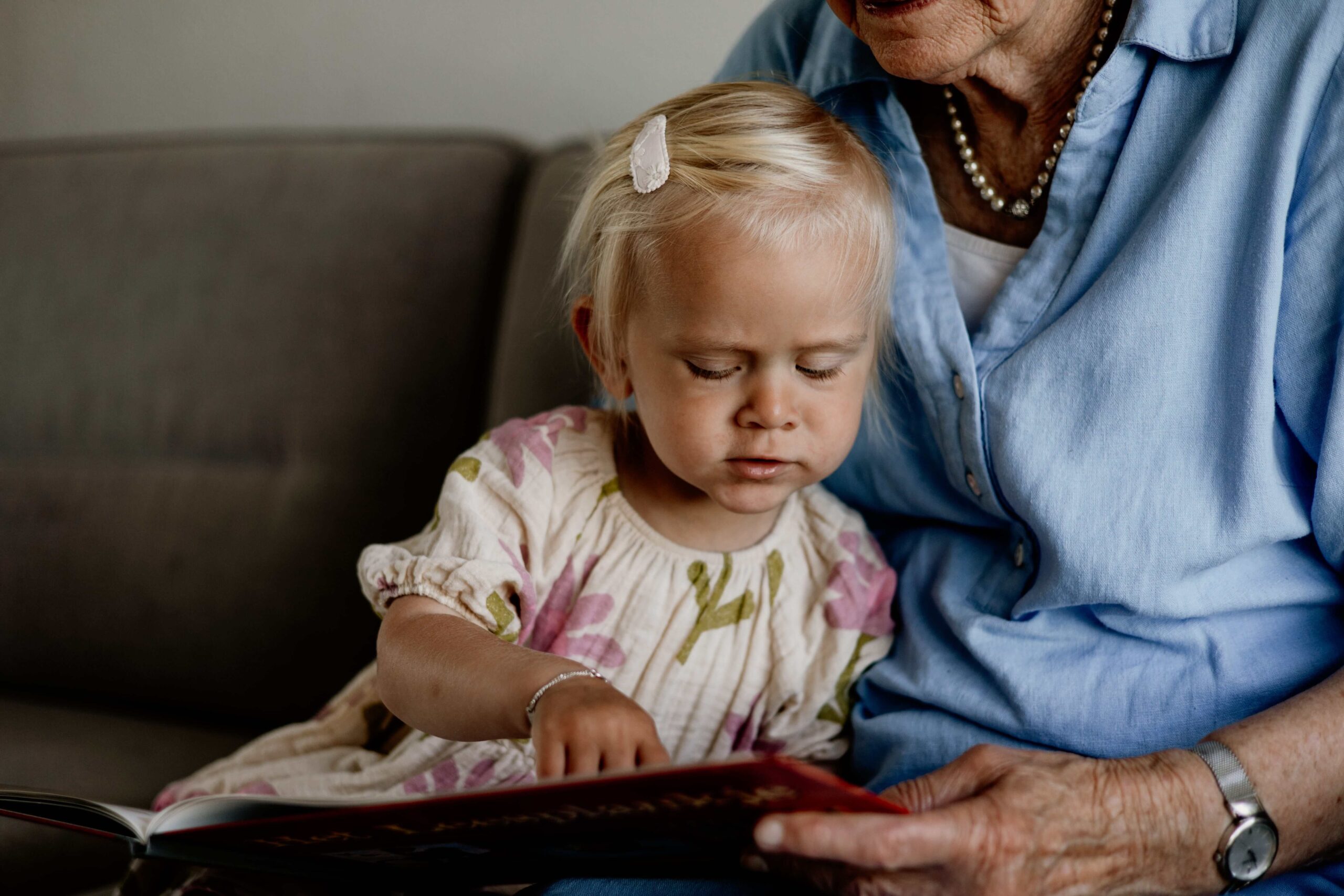 Kleinkind leest een boekje bij oma op schoot