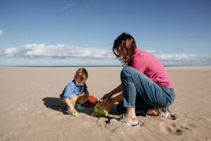 Day in the life fotografie_Moeder en zoon spelen op het strand